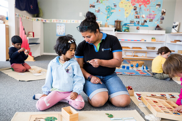 Kaiako and child doing a puzzle together on the mat.